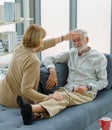 Caucasian old senior elderly supportive wife sitting use hand testing temperature from unhealthy gray bearded and hair husband Royalty Free Stock Photo