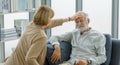 Caucasian old senior elderly supportive wife sitting use hand testing temperature from unhealthy gray bearded and hair husband Royalty Free Stock Photo