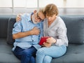 Caucasian old senior elderly unhealthy unwell gray hair and bearded husband sitting together with wife suffering from heart attack