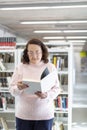 Caucasian older woman reading a book in a public library Royalty Free Stock Photo