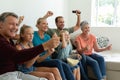 Caucasian parents, grandparents and grandchildren sitting on couch watching tv and cheering Royalty Free Stock Photo