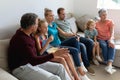 Caucasian parents, grandparents and grandchildren sitting on couch watching tv and eating popcorn Royalty Free Stock Photo