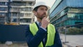 Caucasian pensive adult man heavy metal building industry worker inspector thinking architect looking at skyscrapers