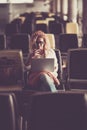 Caucasian people beautiful middle age young woman sit down on a wait seats at the airport or station using personal modern laptop