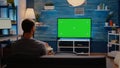 Caucasian person looking at green screen tv