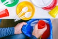 Caucasian person man throwing a plastic cup in blue garbage bag.