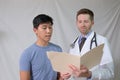 Caucasian Physician examining chart with Asian patient