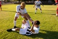 Caucasian player giving hand to injured teammate lying on field in getting up during match