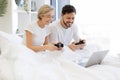 Caucasian playing video games while lying under blanket at home. Royalty Free Stock Photo