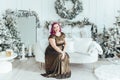 Caucasian plus size model woman in long golden olive color dress sitting on couch celebrating Christmas or New Year