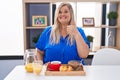 Caucasian plus size woman eating breakfast at home doing happy thumbs up gesture with hand