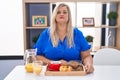 Caucasian plus size woman eating breakfast at home relaxed with serious expression on face