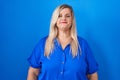 Caucasian plus size woman standing over blue background relaxed with serious expression on face