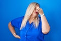 Caucasian plus size woman standing over blue background tired rubbing nose and eyes feeling fatigue and headache