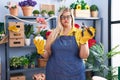 Caucasian plus size woman working at florist shop puffing cheeks with funny face