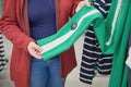 Pregnant woman chooses loose green pants with white stripes in store to buy