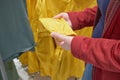 Caucasian pregnant woman chooses yellow windbreaker from rain in store to buy