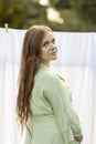 Caucasian pregnant woman hanging up laundry on clothes line outside, drying bed linens Royalty Free Stock Photo