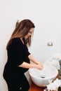 Caucasian pregnant woman smiling and washing hands at home using disinfectant and soap