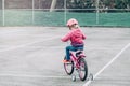 Preschooler girl riding pink bike bicycle in helmet on backyard road outside on spring autumn day Royalty Free Stock Photo