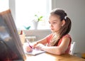 Caucasian preteen girl concentrated on her task with schoolbook. Concept of distance learning in isolation while coronavirus