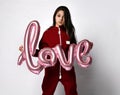 Caucasian preteen girl model in tracksuit holding love letter shaped balloon Royalty Free Stock Photo