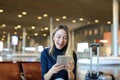 Caucasian pretty woman sitting in airport waiting room with valise and using tablet. Royalty Free Stock Photo