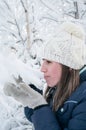 Caucasian woman touching snow cap on tree branch with her mittens, side view, winter season