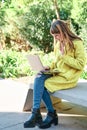 Caucasian pretty young girl, dressed in a yellow jacket, a white sweater, making a video conference with the laptop sitting on a Royalty Free Stock Photo