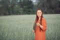 Caucasian red-haired woman in a red dress walking on a farm field with wheat at sunset on a summer day.future organic food crop Royalty Free Stock Photo