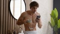 Caucasian relaxed naked man drink tea at morning routine reading news in social media in smartphone browsing at mobile Royalty Free Stock Photo