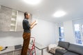Caucasian repair master electrician man standing in apartment at stepladder