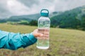 caucasian 50s blonde girl drinking water from plastic bottle. Mountain background