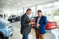 Caucasian salesman holding clipboard and talking about buying car with sale with his customer Royalty Free Stock Photo