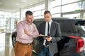 Caucasian salesman holding clipboard and talking about buying car with sale with his customer Royalty Free Stock Photo