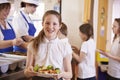 Caucasian schoolgirl holds plate of food in school cafeteria