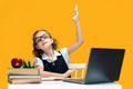 Caucasian schoolgirl raises hand up sits at laptop during online lesson. Distant School Learning. Royalty Free Stock Photo