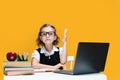 Caucasian schoolgirl raising hand sitting at laptop during online lesson. Distant School Learning. Royalty Free Stock Photo