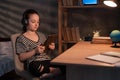 Caucasian schoolgirl watching something on tablet computer at night, preteen girl in wireless headphones using digital Royalty Free Stock Photo