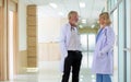 Caucasian senior beard male and female doctors wearing white gown uniforms with stethoscope, consulting, talking to each other in