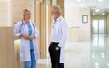 Caucasian senior beard male and female doctors wearing white gown uniforms with stethoscope, consulting, talking to each other in