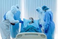 Caucasian senior coronavirus covid-19 infected patient lying on bed in quarantine room of hospital with doctor and medical staffs