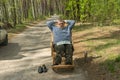 Senior driver resting outside of his car sleeping in a wicker rocking-chair in spring forest Royalty Free Stock Photo