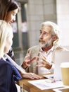 Caucasian senior executive talking to two business women