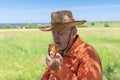 Caucasian senior farmer eating handmade patty under tree shadow near his field