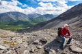 Caucasian senior hiker sitting and resting on stone when climbing to the height of the mountain Royalty Free Stock Photo