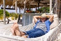 Caucasian senior man with hands behind head sleeping on hammock at beach Royalty Free Stock Photo