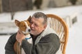Caucasian senior man with his cute basenji dog sitting in wicker chair at sunny winter day Royalty Free Stock Photo