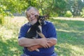 Caucasian senior man relaxing while holding black little puppy on the hands Royalty Free Stock Photo