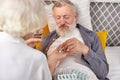 Caucasian Senior man taking medicines and drinking water while lie on bed, wife help and support Royalty Free Stock Photo